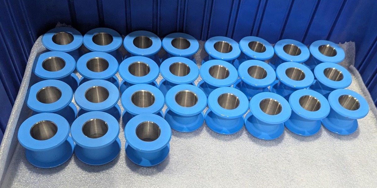 Rows of helicopter parts with a coating of blue epoxy rest on paper inside of a dark blue box