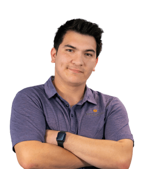 Smiling young man with short dark hair, arms crossed, wearing a purple polo and a smartwatch against a white background.