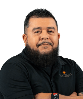 Portrait of a man with a full beard in a black polo shirt bearing a Bertrand logo, arms crossed, looking at the camera.